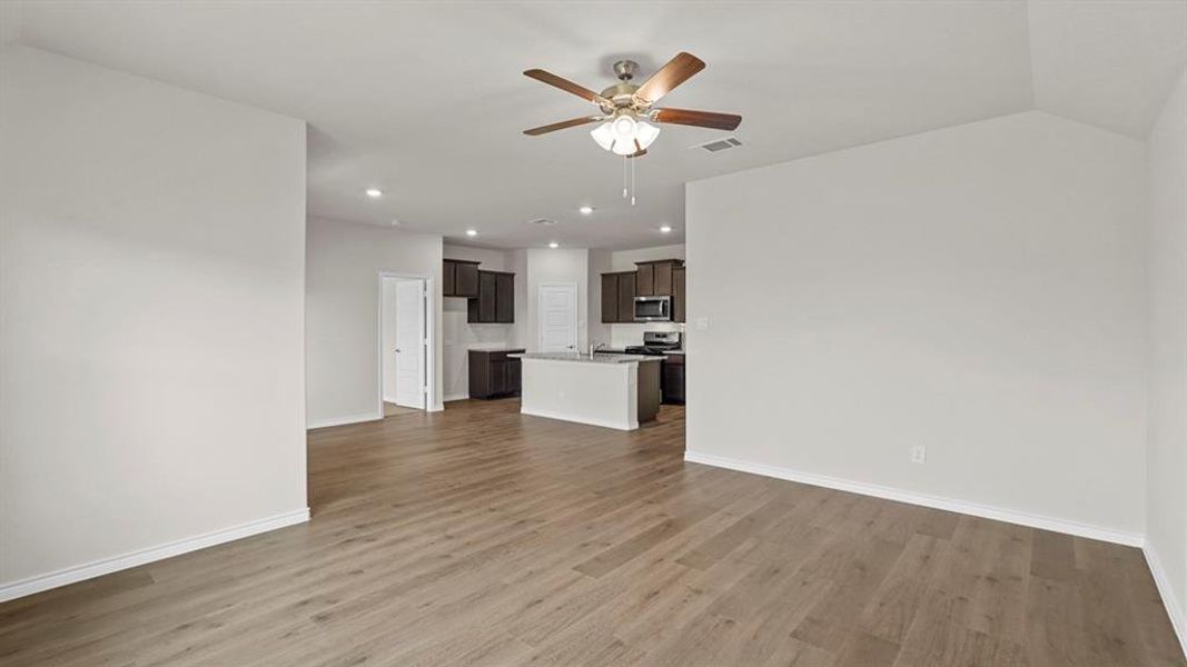 Open-concept living area featuring wood-finish flooring, a ceiling fan with integrated lighting, and recessed lighting