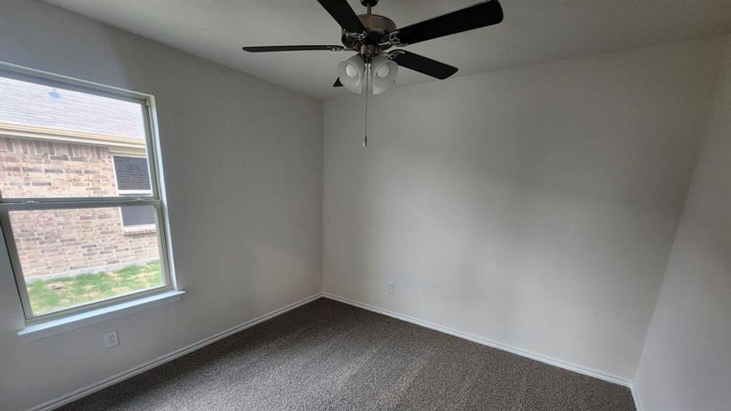 Carpeted room featuring a ceiling fan with light fixture, a double-hung window, and white trim