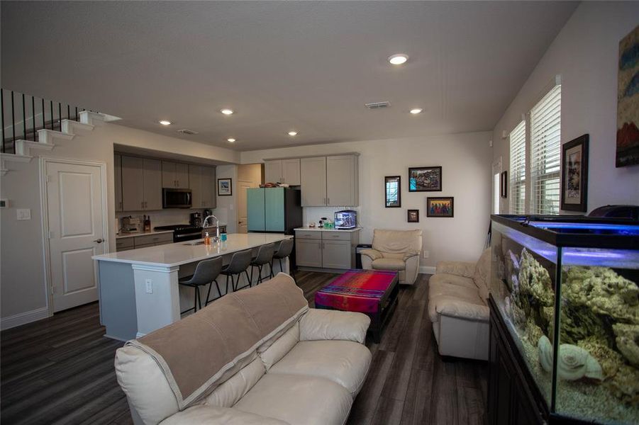 Living area featuring visible vents, baseboards, recessed lighting, dark wood-style flooring, and stairs