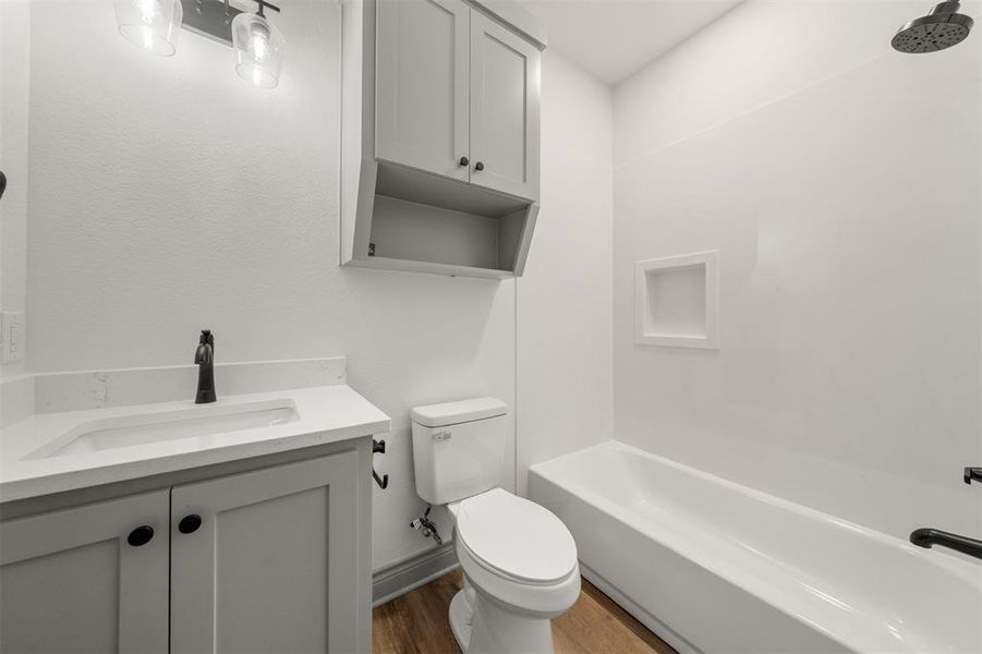 Bathroom featuring vanity, shower / bath combination, and wood finished floors