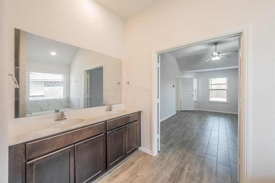Full bath with double vanity, dark wood-style flooring, a ceiling fan, and lofted ceiling Full bath with double vanity, dark wood-style flooring, a ceiling fan, and lofted ceiling