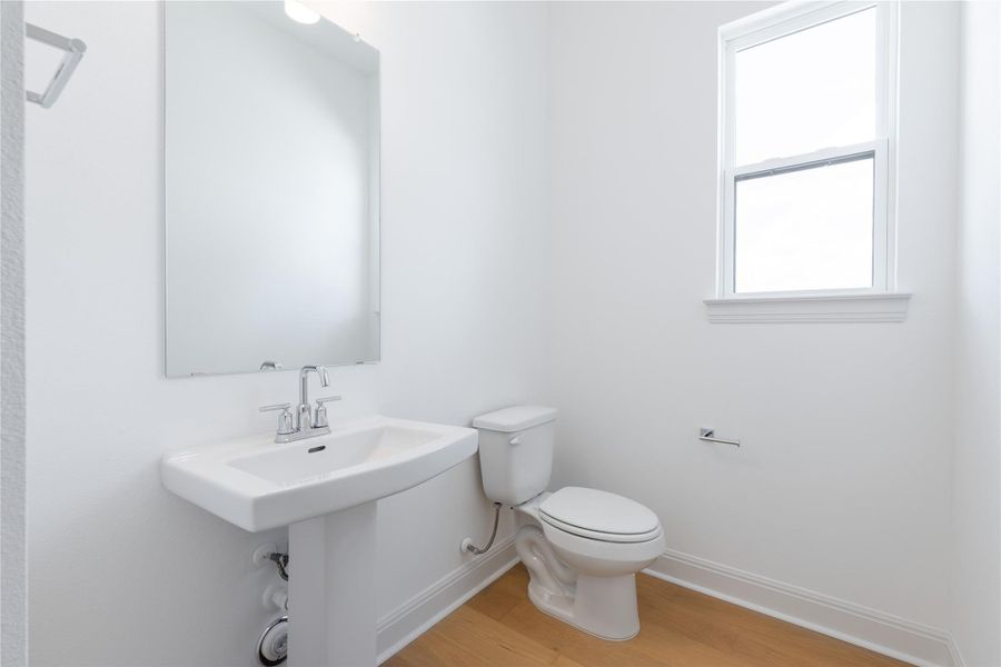 Half bath featuring toilet and light wood finished floors