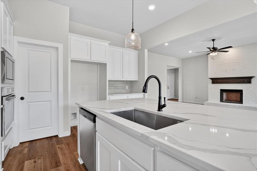 Spacious kitchen island featuring a deep undermount sink with a matte black faucet, stainless steel dishwasher, and stone-finish countertop