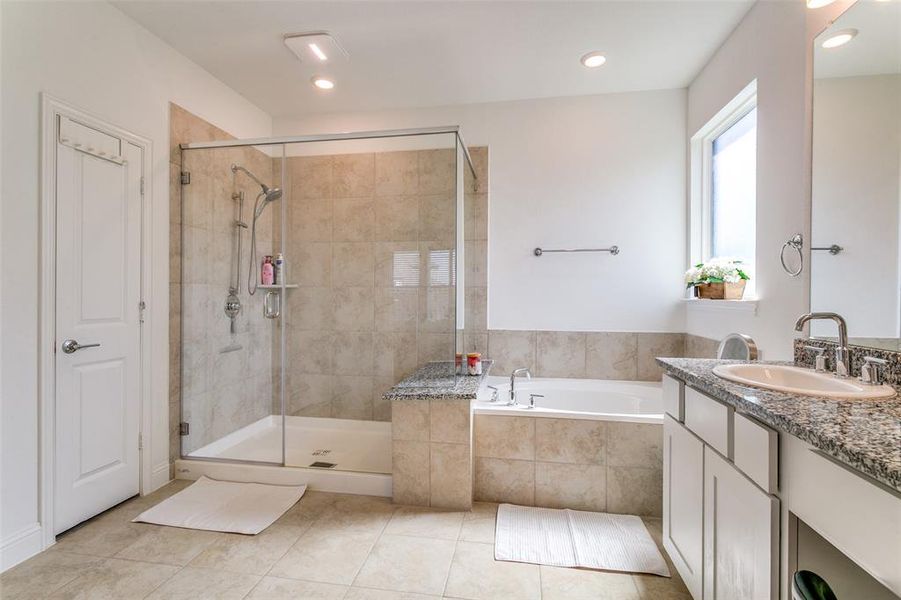 Bathroom featuring vanity, a bath, a stall shower, light tile patterned floors, and recessed lighting