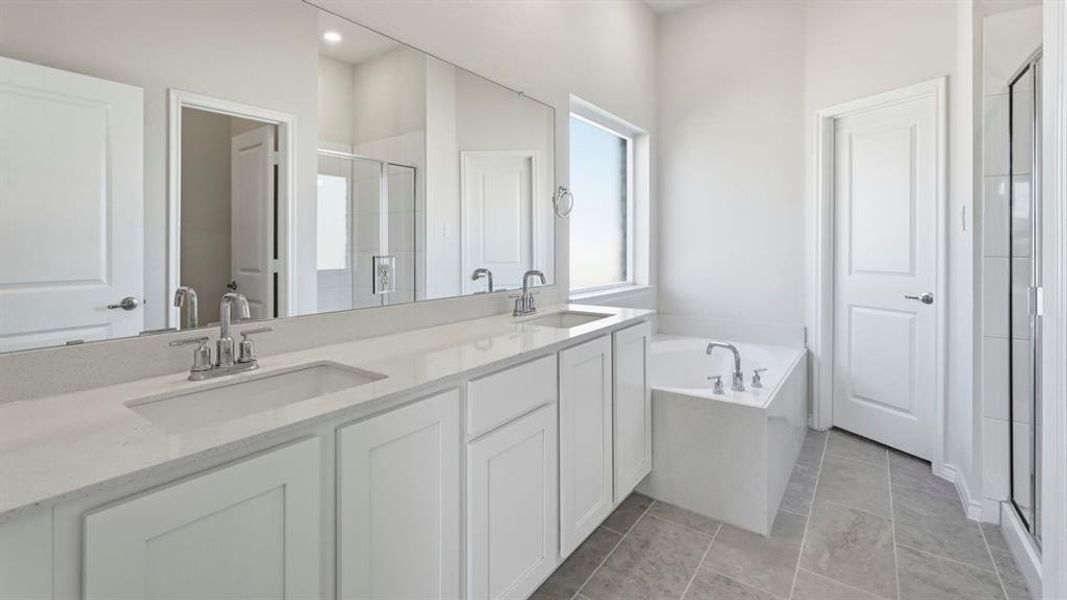 Well-appointed bathroom featuring a double vanity with ample counter space, a built-in bathtub, and a separate glass-enclosed shower Well-appointed bathroom featuring a double vanity with ample counter space, a built-in bathtub, and a separate glass-enclosed shower
