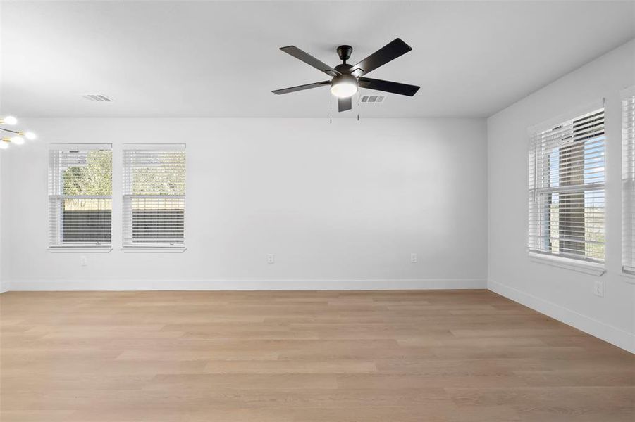 Spare room featuring light hardwood / wood-style floors and ceiling fan with notable chandelier