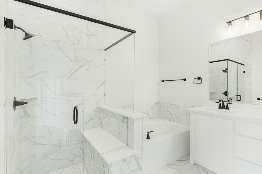 Bathroom with marble tile, glass walk-in shower, soaking tub, and white vanity with black fixtures