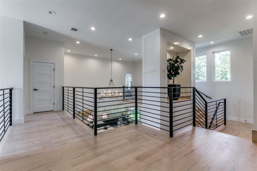 Corridor with light hardwood / wood-style floors and an inviting chandelier