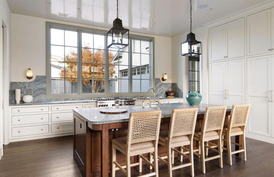Kitchen featuring dark stone countertops, a center island with sink, decorative backsplash, and a breakfast bar area Kitchen featuring dark stone countertops, a center island with sink, decorative backsplash, and a breakfast bar area