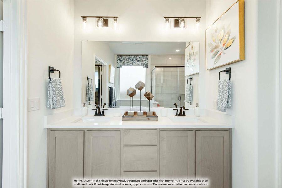 Bathroom double vanity with gray cabinets, white countertop, two sinks, large mirror, and wall sconce lighting