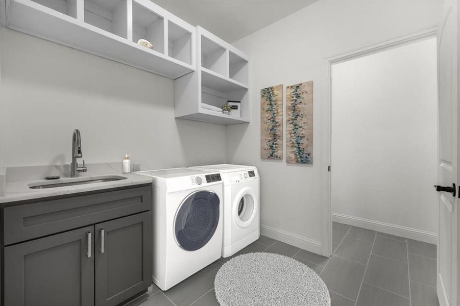 Clothes washing area with cabinets, dark tile patterned flooring, sink, and washer and dryer