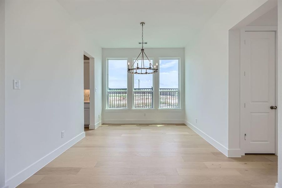 Unfurnished dining area featuring a chandelier, light wood-style flooring, and baseboards