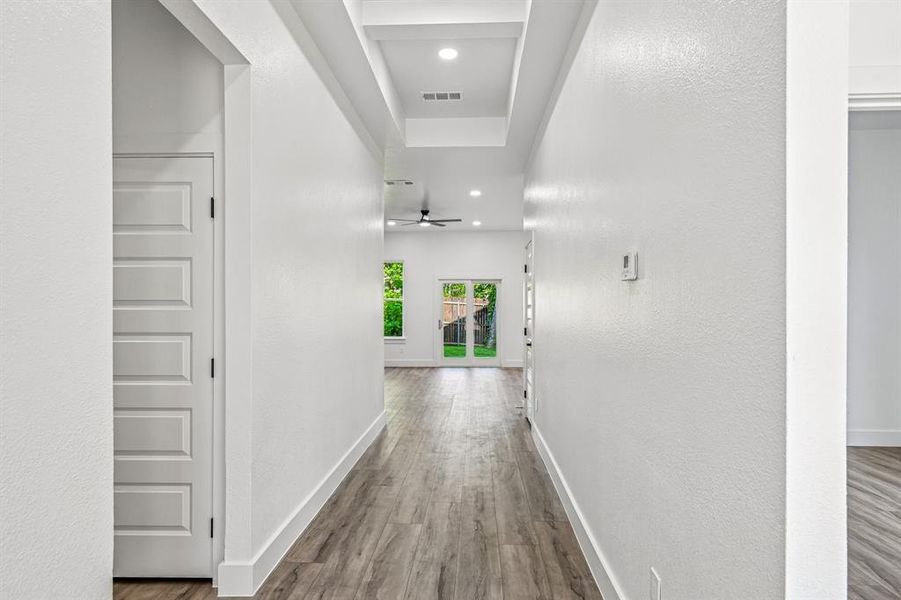 Hallway featuring wood-finish flooring, white walls, and a multi-paneled interior door