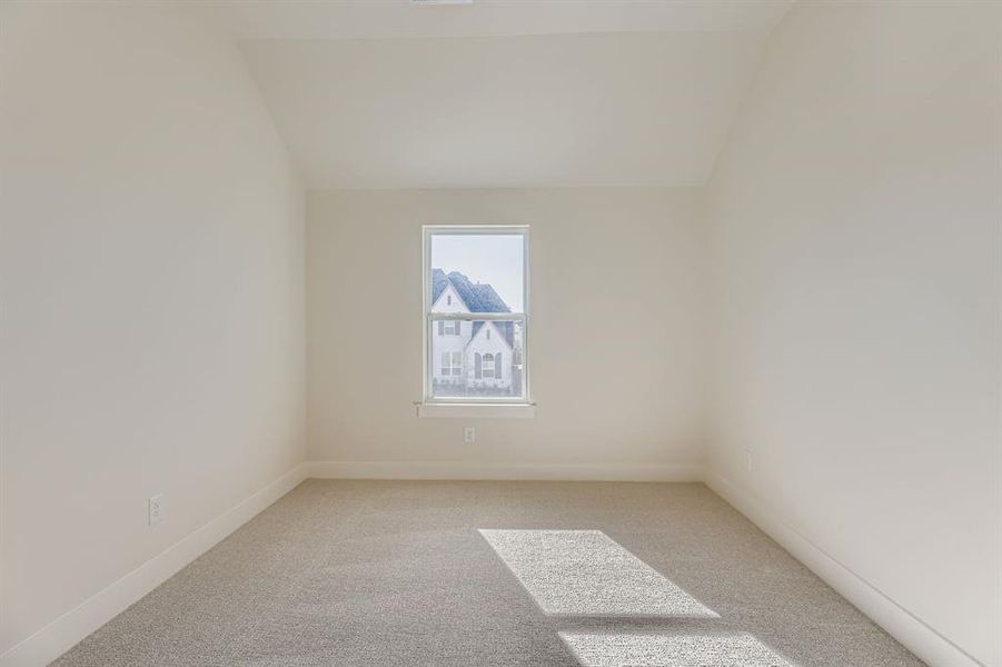 Additional living space featuring light carpet and vaulted ceiling