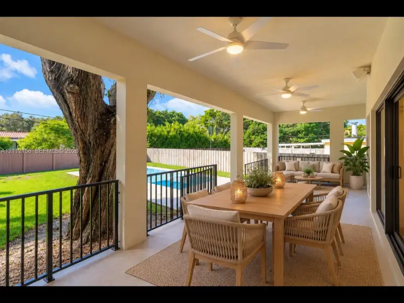 Covered patio made for year-round outdoor living, with three lighted ceiling fans, overlooking the pool and fenced backyard