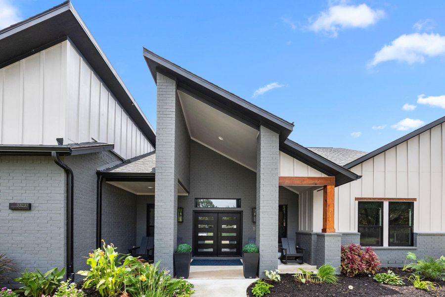 Modern home with a sleek exterior featuring a combination of gray brick and light paneling. The entrance is inviting with a high, angular roof and a stylish door. Well-maintained landscaping adds curb appeal. Modern home with a sleek exterior featuring a combination of gray brick and light paneling. The entrance is inviting with a high, angular roof and a stylish door. Well-maintained landscaping adds curb appeal.
