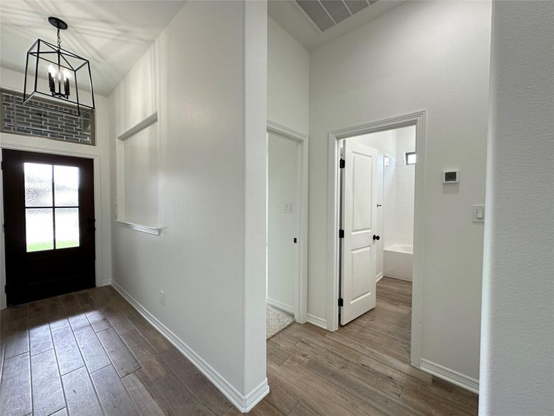 Entryway featuring dark wood-style floors, a chandelier, and a high ceiling
