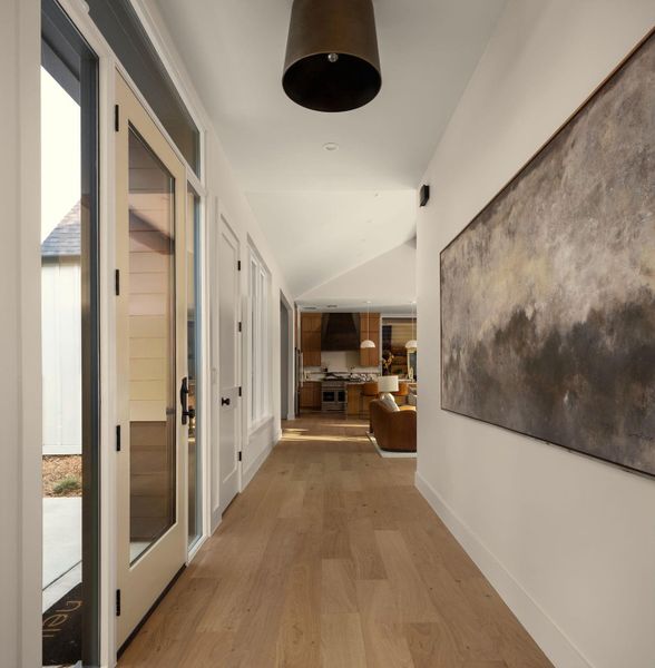 A spacious entry hallway features elegant hardwood flooring, guiding the eye towards an open concept kitchen and living area. A spacious entry hallway features elegant hardwood flooring, guiding the eye towards an open concept kitchen and living area.