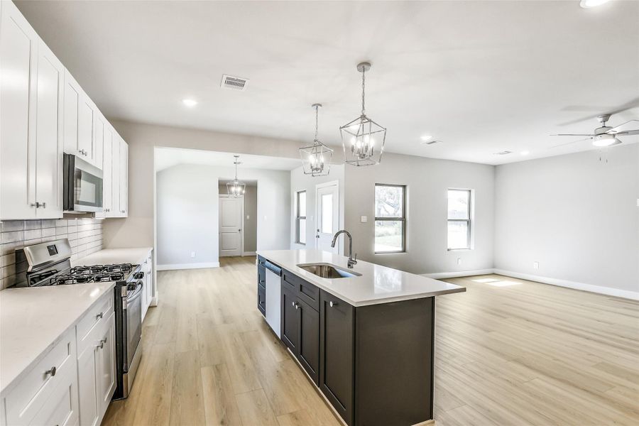 Open-concept layout with seamless flow from the kitchen to the living and dining areas, featuring recessed lighting throughout and abundant natural light.