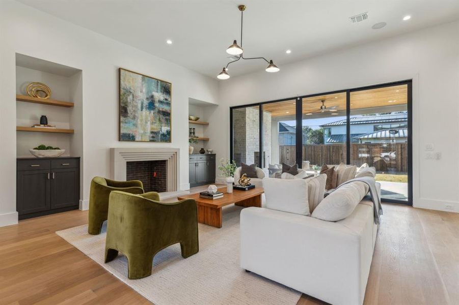 Living room with ceiling fan, light hardwood / wood-style floors, and built in features