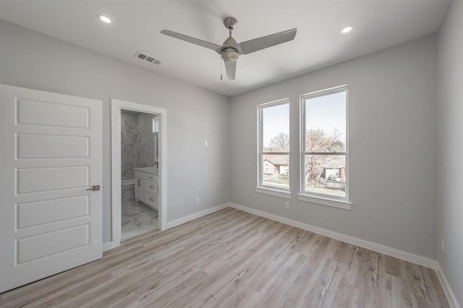 Unfurnished bedroom with light wood-type flooring, ceiling fan, and ensuite bathroom