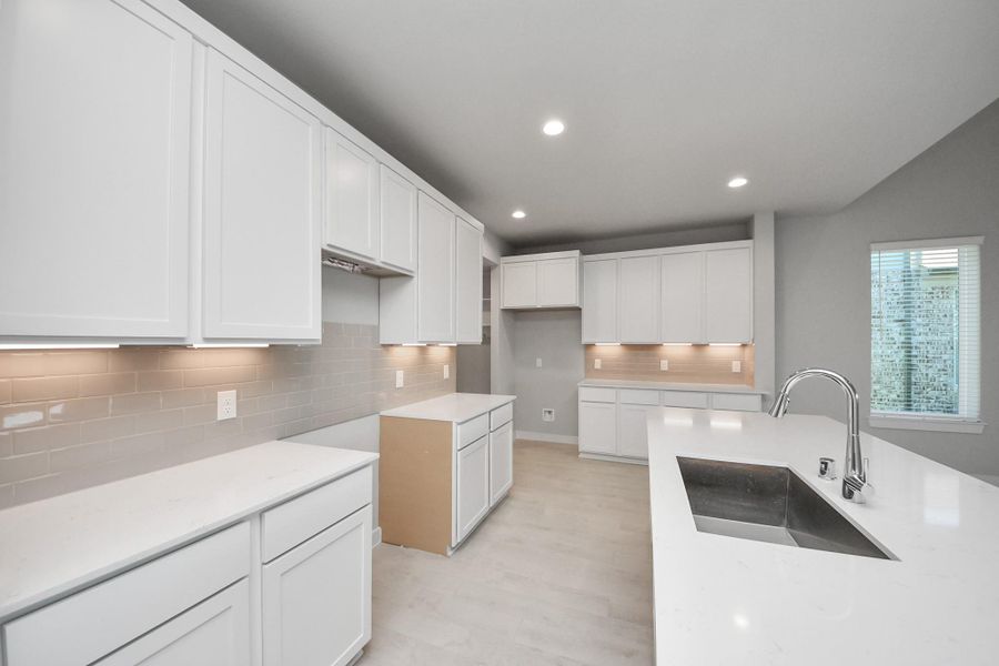 Discover another perspective of this stunning kitchen, generously appointed with an abundance of counter space. Sample photo of completed home with similar floor plan. Actual colors and selections may vary.