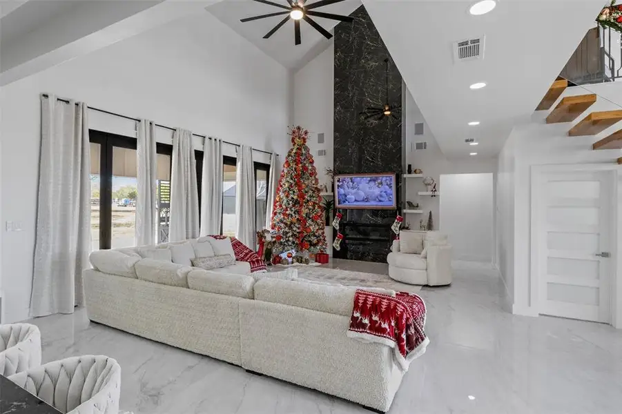 Living area featuring high vaulted ceiling, a premium fireplace, ceiling fan, marble tiled flooring, and recessed lighting Living area featuring high vaulted ceiling, a premium fireplace, ceiling fan, marble tiled flooring, and recessed lighting