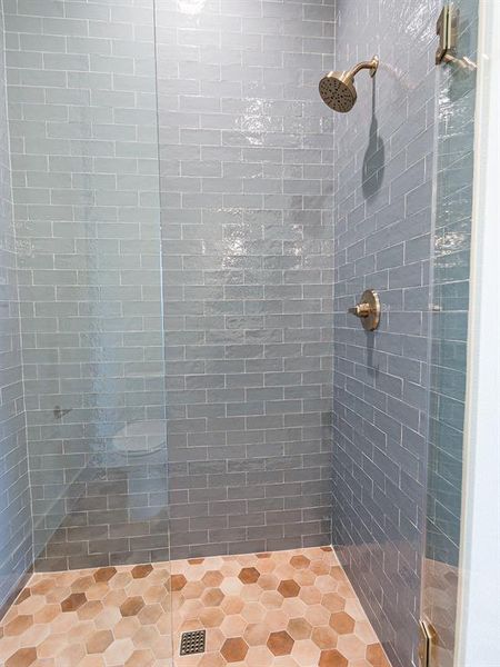 Matching shower with textured tiled walls and earth tone floor tile.