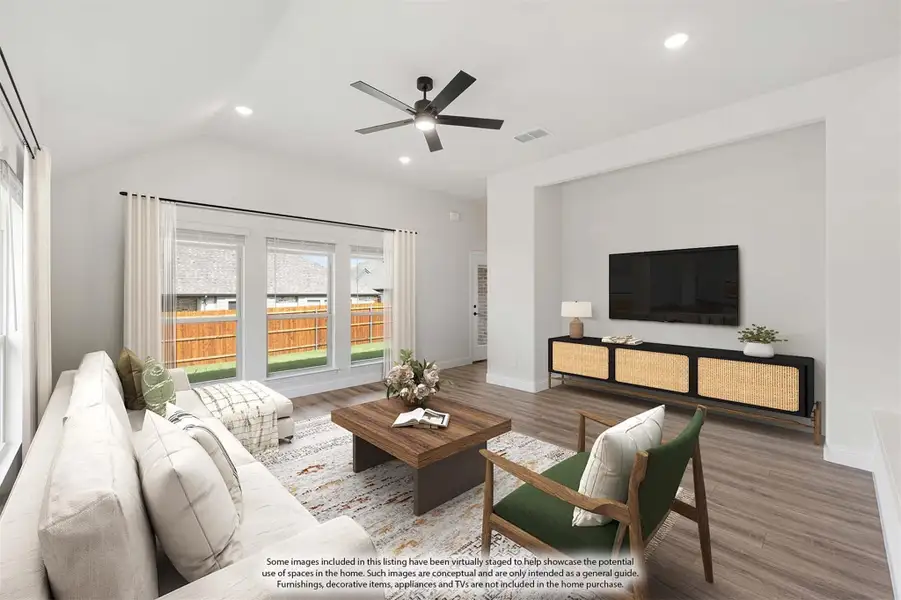 Living room with vaulted ceiling, ceiling fan, hardwood floors, and large windows overlooking backyard