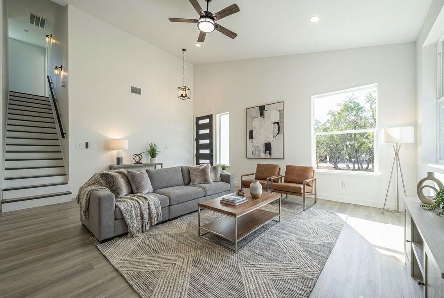 Living room with wood finished floors, stairs, high vaulted ceiling, ceiling fan, and recessed lighting