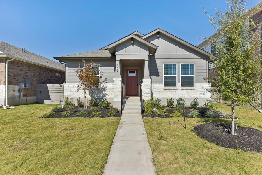 View of front of property with board and batten siding, a front lawn, and stone siding