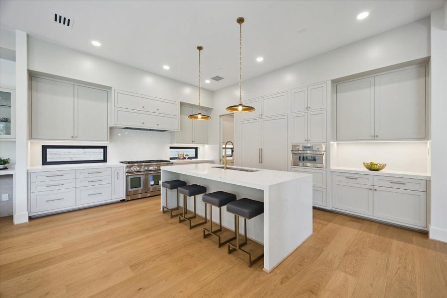 Spacious kitchen with stainless steel appliances and modern waterfall island. Spacious kitchen with stainless steel appliances and modern waterfall island.