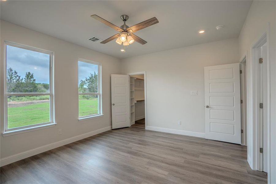 Unfurnished bedroom featuring wood-type flooring, a spacious closet, ceiling fan, and a closet