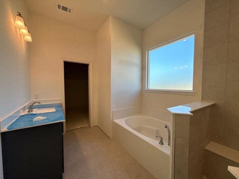 Bathroom featuring vanity, a bath, and light tile patterned flooring