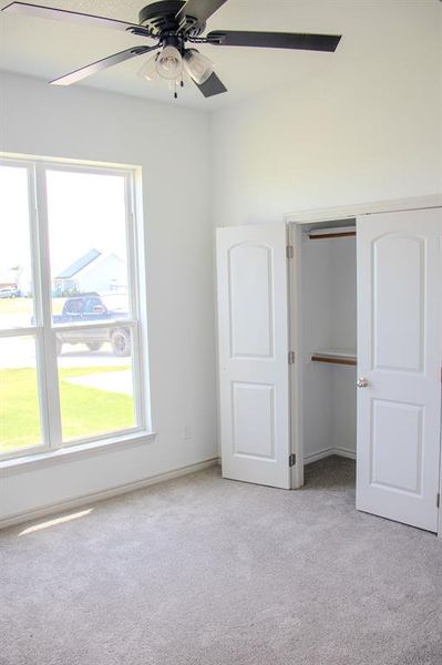 Unfurnished bedroom with light carpet, ceiling fan, and a closet Unfurnished bedroom with light carpet, ceiling fan, and a closet