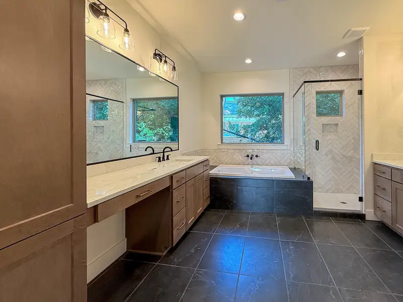 A spa-like primary suite featuring a lavish 5-piece bath with dual vanities, a deep soaking tub, and a separate glass-enclosed shower leading into a spacious walk-in closet designed for extensive wardrobes.