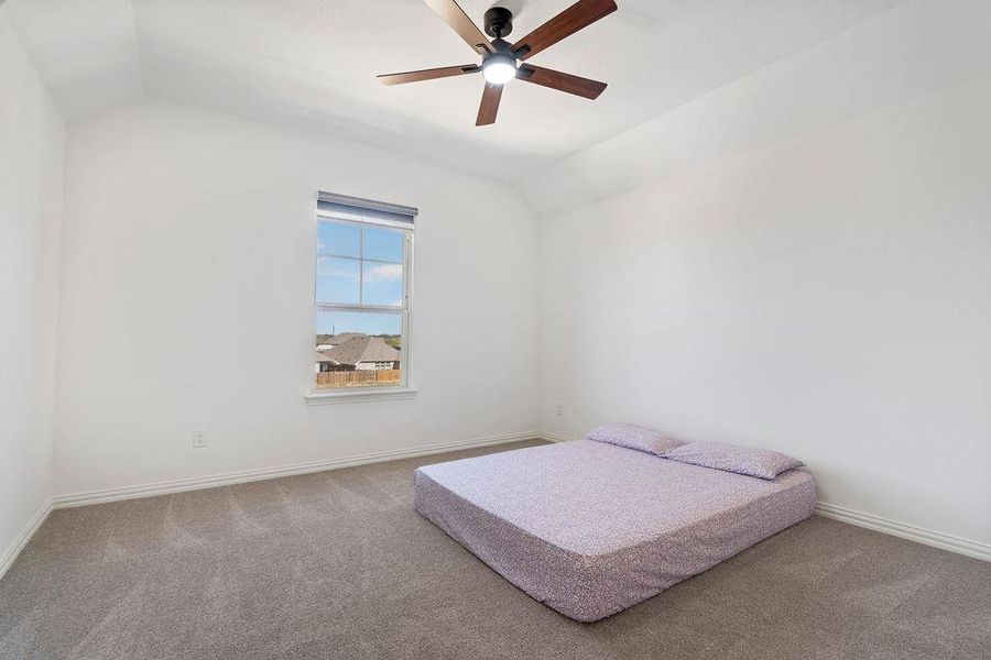 Bedroom with vaulted ceiling, ceiling fan, and carpet flooring Bedroom with vaulted ceiling, ceiling fan, and carpet flooring