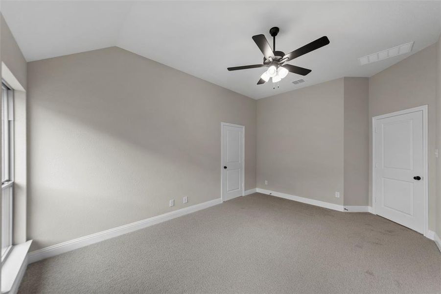 Spacious room featuring vaulted ceilings, light gray carpeting, and neutral-toned walls