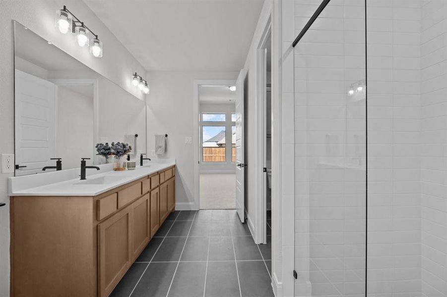 Double vanity with light wood-finish cabinetry, white countertops, and matte black fixtures Double vanity with light wood-finish cabinetry, white countertops, and matte black fixtures