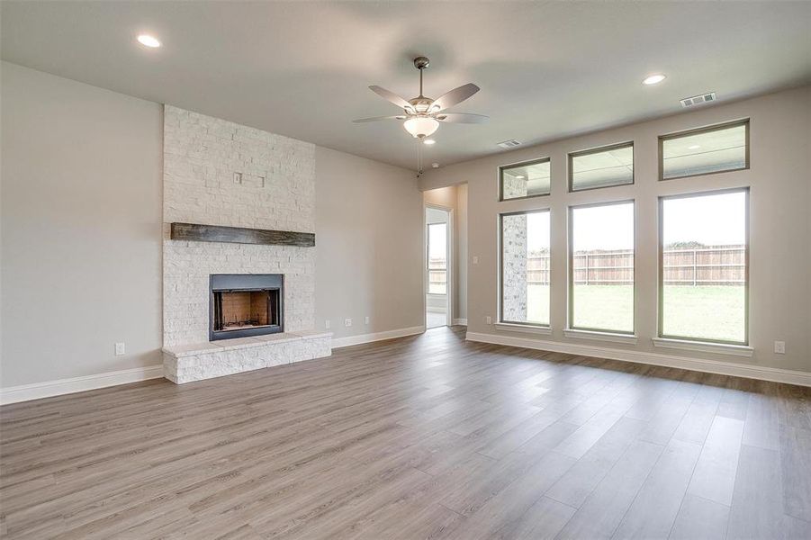 Unfurnished living room featuring a stone fireplace, hardwood / wood-style flooring, and ceiling fan