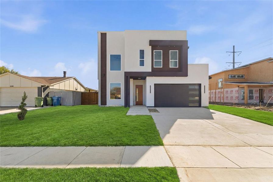 Contemporary house with stucco siding, driveway, a front lawn, and a garage