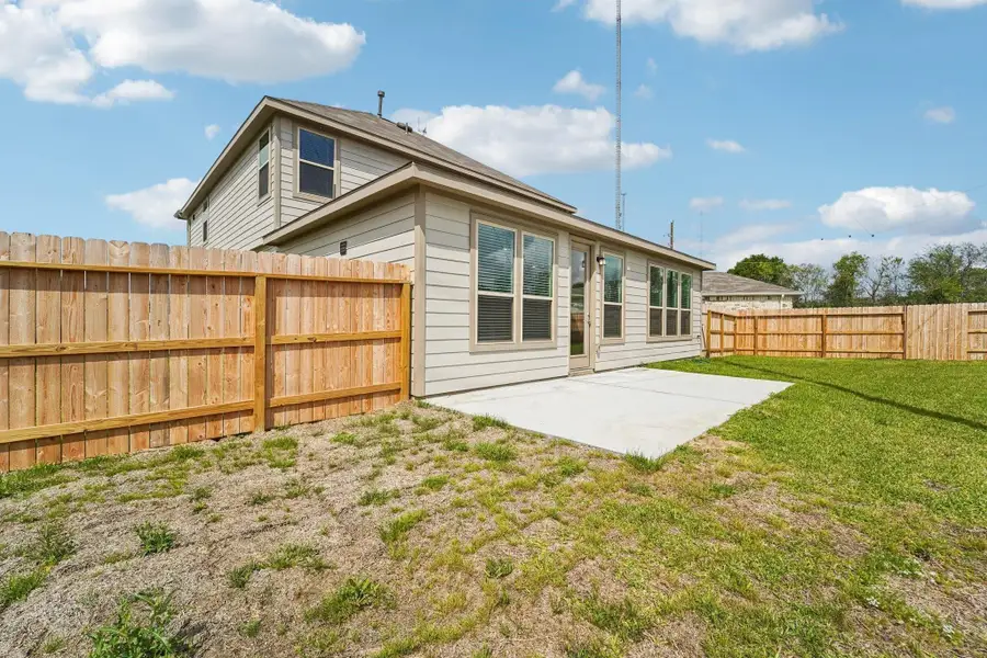 The backyard features a pristine concrete patio slab, providing a clean and durable foundation for your customized outdoor retreat. This functional extension of the home serves as the perfect transition between the indoor living space and the expansive green lawn.