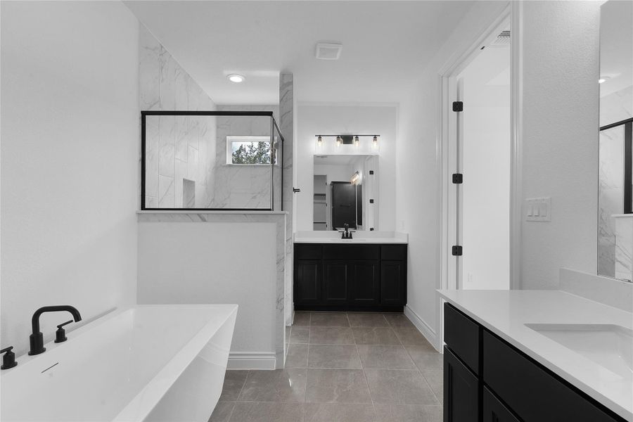 Bathroom with a freestanding tub, two vanities, and a marble finish shower