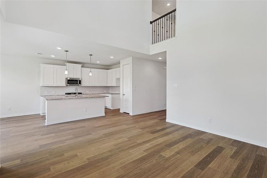 Unfurnished living room featuring wood-type flooring and a towering ceiling