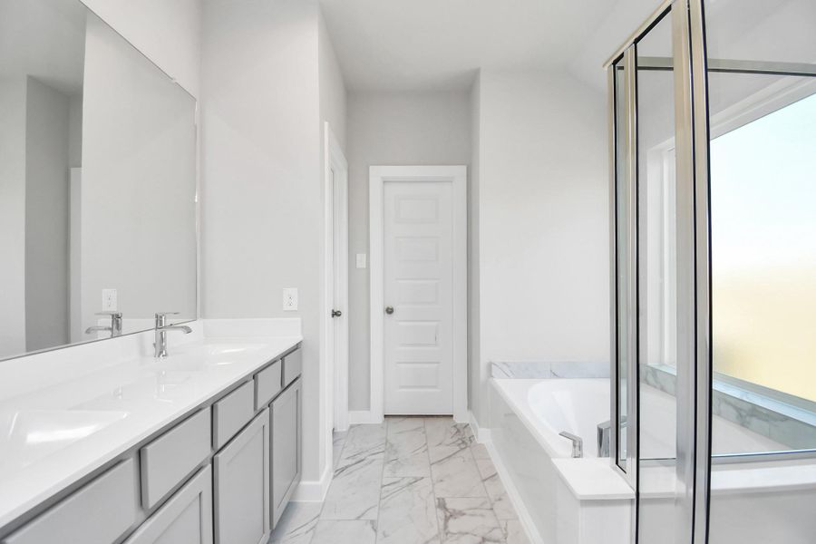 Immerse yourself in a luxurious retreat within the confines of your main bathroom. Enjoy the roomy walk-in shower encased in stylish tile, take a moment to unwind in a separate garden tub embellished with custom details, and elevate your daily routine at the refined vanity, now boasting double sinks, light-toned countertops, modern hardware, and bright recessed lights. Sample photo of completed home with similar floor plan. As-built interior colors and selections may vary. Immerse yourself in a luxurious retreat within the confines of your main bathroom. Enjoy the roomy walk-in shower encased in stylish tile, take a moment to unwind in a separate garden tub embellished with custom details, and elevate your daily routine at the refined vanity, now boasting double sinks, light-toned countertops, modern hardware, and bright recessed lights. Sample photo of completed home with similar floor plan. As-built interior colors and selections may vary.