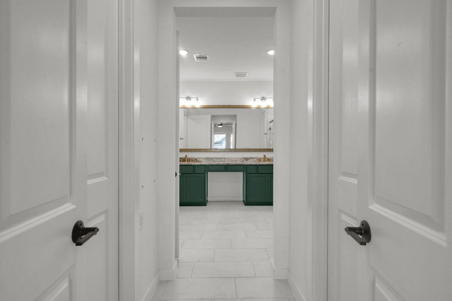 The double doors lead to the primary bath with tile flooring and walk-in closets with closet system built-ins.