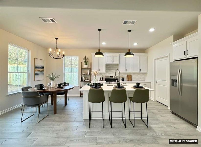 Kitchen with a kitchen island with sink, backsplash, stainless steel appliances, white cabinets, and a kitchen bar Kitchen with a kitchen island with sink, backsplash, stainless steel appliances, white cabinets, and a kitchen bar