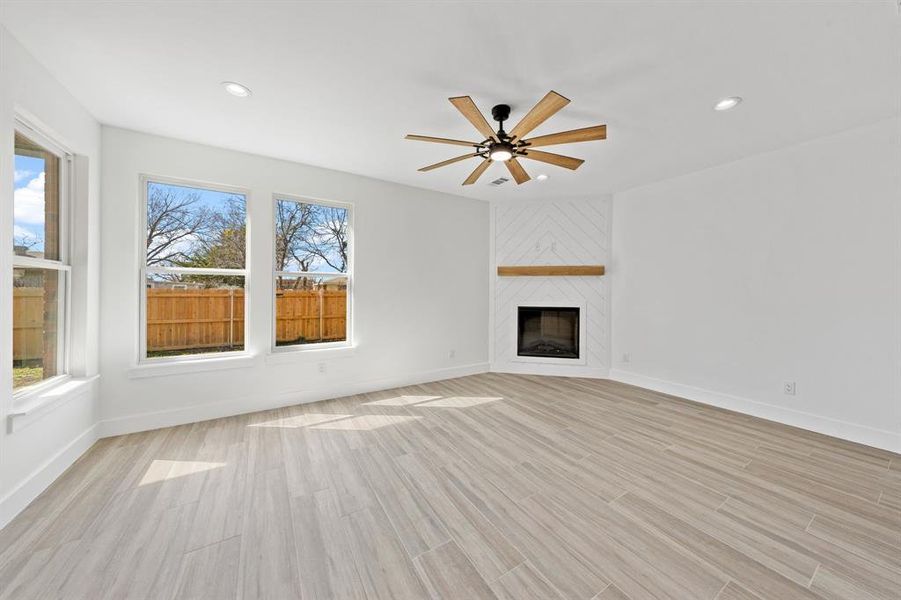 Unfurnished living room with a large fireplace, recessed lighting, light wood-type flooring, and a healthy amount of sunlight