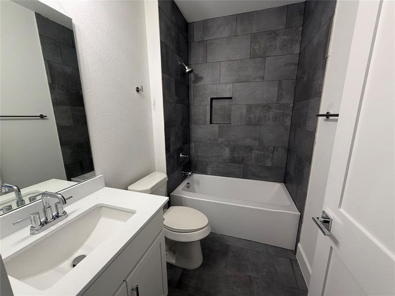 Bathroom featuring a textured wall, vanity, and shower / washtub combination