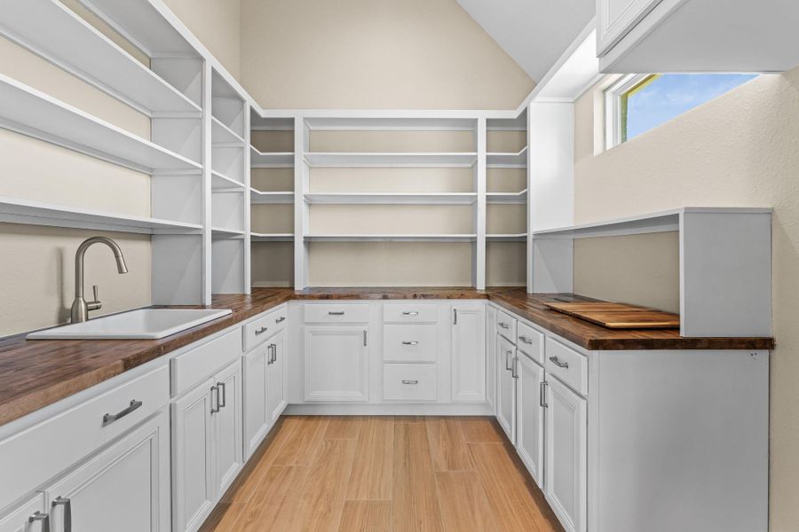Functional butler’s pantry with extra counter space, open shelving, and easy access between kitchen and dining areas.